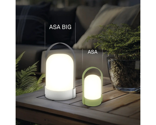 Två moderna bärbara LED-bordslampor ASA BIG och ASA i plast på ett träbord i ett ljust, organiserat utomhusområde.