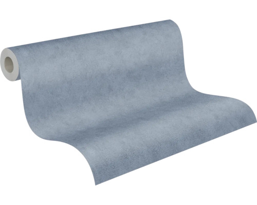 Blå non-woven tapet med strukturerad yta i betonglook, något utrullad.