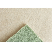 Grön heltäckningsmatta med strukturerad yta och beige filtbaksida. Detaljbild av materialstrukturen.