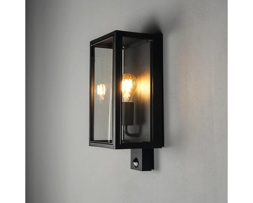 Svart vägglampa i lådform med klart glas och rörelsesensor för utomhusbruk.