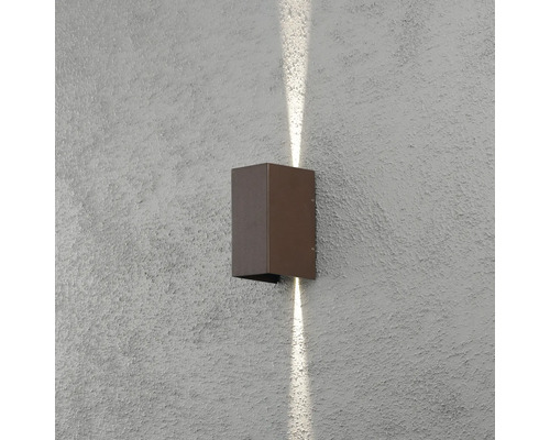 Modern rektangulär vägglampa med ljussken uppåt och nedåt på en strukturerad vägg.