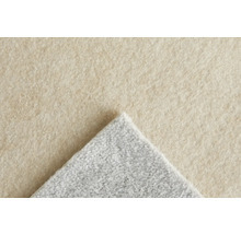 Närbild av en matta med beige yta och grå baksida.