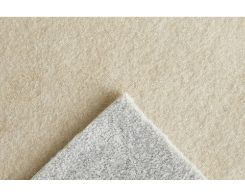Närbild av en matta med beige yta och grå baksida.