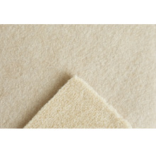 Närbild på strukturen hos en beige nålfiltsmatta med ett uppvikt hörn.
