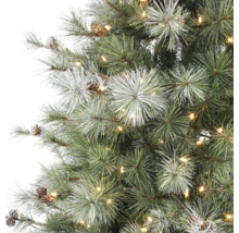 Detalj av konstgjord julgran med varmvita LED-lampor, kottar och snötäckta barr.