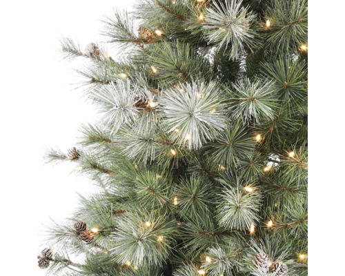 Detalj av konstgjord julgran med varmvita LED-lampor, kottar och snötäckta barr.