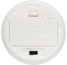 Undersidan av en vit elektronisk enhet med batterifack för två AA batterier och en brytare för på, av och timerfunktion.