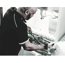Man som använder en momentnyckel för justering på en industrimaskin i en verkstad.
