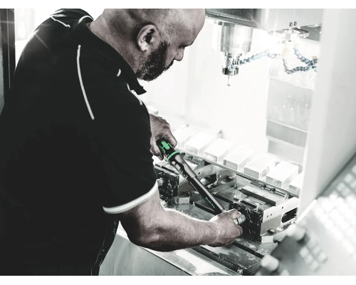 Man som använder en momentnyckel för justering på en industrimaskin i en verkstad.