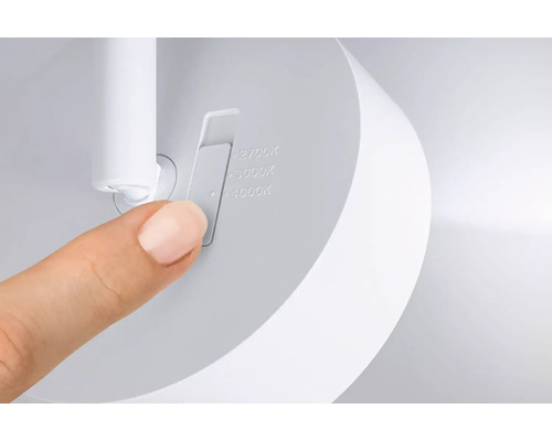 Ett finger som ställer in färgtemperatur på en vit lampa mellan 2700 Kelvin, 3000 Kelvin och 4000 Kelvin med ett skjutreglage.