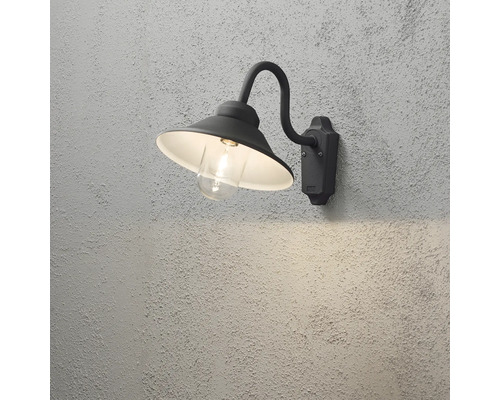 Svart utomhusvägglampa i klassisk design med böjd arm, konisk skärm och klart skyddsglas.