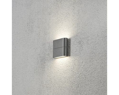 Modern LED-vägglampa för utomhusbruk i antracit, belysning uppåt och nedåt på en fasad, varmvitt ljus.