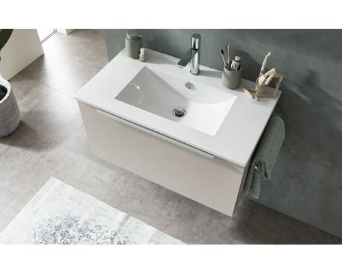 Modern vägghängd kommod med vitt tvättställ, beige underskåp och kromad blandare i ett ljust badrum.