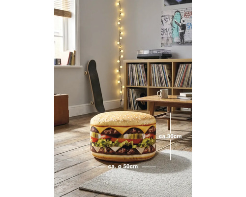 En rund sittpuff i hamburgerdesign, cirka 30 centimeter hög och cirka 50 centimeter i diameter, i ett ljust rum med trägolv.