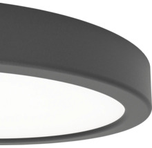 Detaljvy av en rund, platt LED-taklampa med mörkgrå, strukturerad ram och vit diffusor.