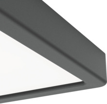 Detaljvy av hörnet på en modern taklampa med mörk metallram och vit diffusor.