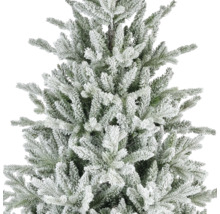 Närbild av en konstgjord julgran med snötäckta grenar och gröna barr.