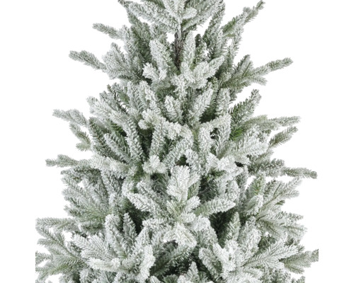 Närbild av en konstgjord julgran med snötäckta grenar och gröna barr.