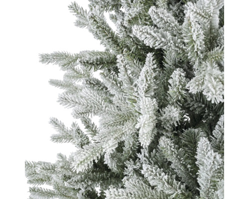 Detaljvy av de snöiga grenarna på en konstgjord julgran för juldekoration.
