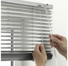 Närbild av en hand som använder en silverfärgad aluminiumpersienn med en genomskinlig vridstång och dragsnöre.