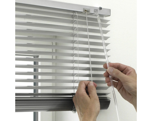 Närbild av en hand som använder en silverfärgad aluminiumpersienn med en genomskinlig vridstång och dragsnöre.