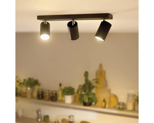 Modern taklampa med tre cylindriska spotlights monterade på en rektangulär skena i ett vardagsrum