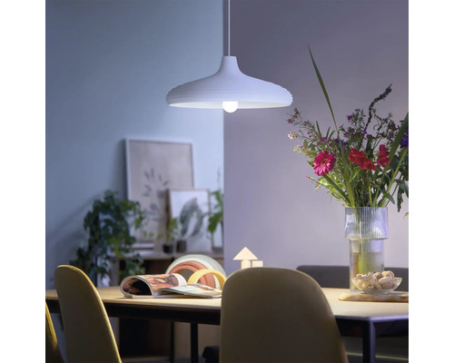 Modern taklampa ovanför ett matbord i en ljus, hemtrevlig matsal med en blombukett och dekorationer.