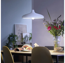 Modern taklampa ovanför ett matbord i en ljus, hemtrevlig matsal med en blombukett och dekorationer.