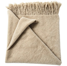 Mjuk pläd med fransar i beige.
