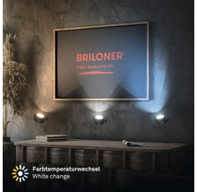 Tre LED väggstrålkastare med justerbar färgtemperatur, monterade under en bild med Briloner logotyp på en texturerad vägg ovanför ett träskåp.