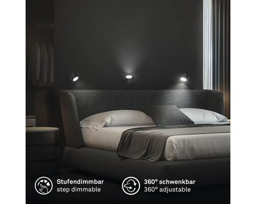 Tre vridbara och stegvis dimbara väggspotlights i ett modernt sovrum ovanför en stoppad dubbelsäng.