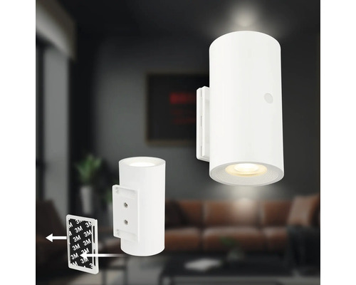 Cylindrisk LED vägglampa i vitt med klistermontering genom 3M tejp framför ett modernt vardagsrum