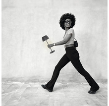 En kvinna med afro frisyr bär en modern bordslampa som en accessoar likt en handväska.