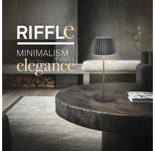 Modern bordslampa med minimalistisk design placerad på ett runt träbord i ett elegant inrett vardagsrum.