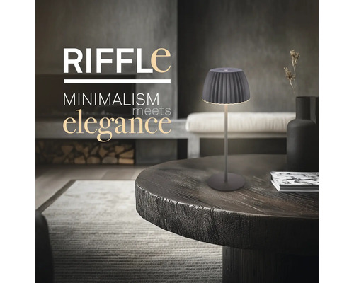 Modern bordslampa med minimalistisk design placerad på ett runt träbord i ett elegant inrett vardagsrum.