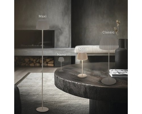 Tre olika storlekar på moderna bordslampor och en golvlampa med veckad skärm i ett minimalistiskt vardagsrum.