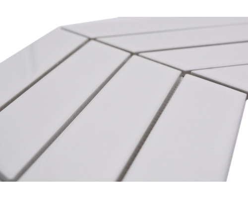 Detaljbild av rektangulära, vita keramikplattor lagda i ett fiskbensmönster.