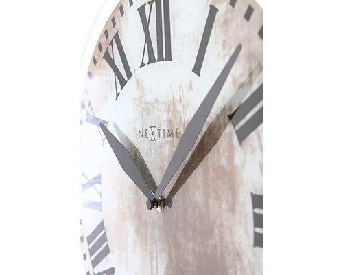 Närbild av en väggklocka med romerska siffror och Nextime-logotypen.