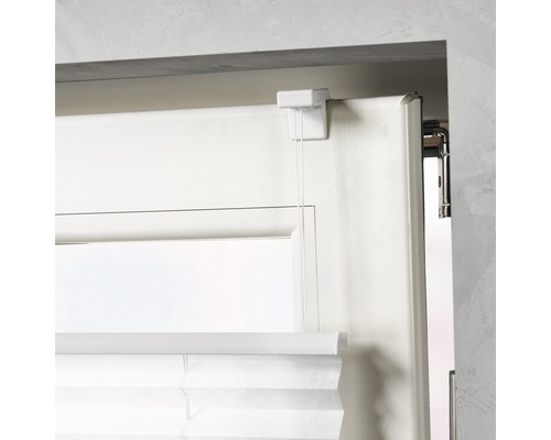 Detalj av en plisségardin på ett fönster med manöverelement