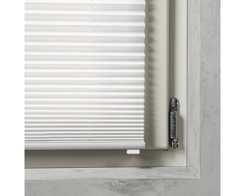 Detalj av en vit plisségardin på ett fönster