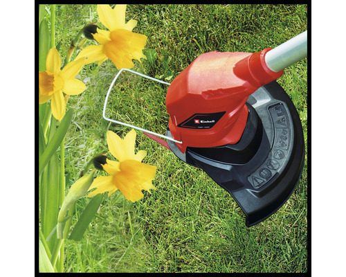 Einhell Logotyp. Grästrimmer i drift på gräsmatta bredvid påskliljor.