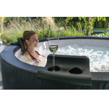 Kvinna kopplar av i bubbelpool med mugghållare och champagneglas