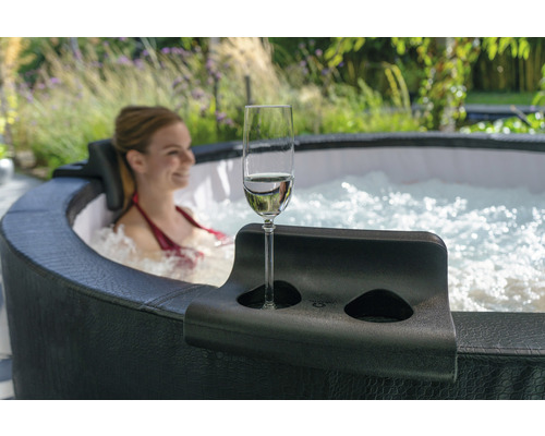 Kvinna kopplar av i bubbelpool med mugghållare och champagneglas
