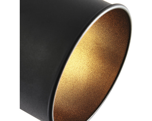 Närbild av en svart cylindrisk lampa med en guldfärgad insida.