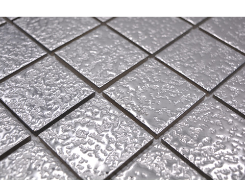 Närbild av kvadratiska, silverfärgade mosaikplattor med en ojämn yta.