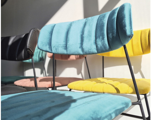 Flera stolar med sammetsklädsel och metallben står i rummet.