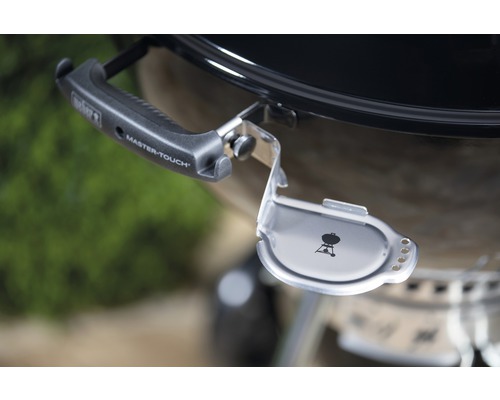 Detaljvy av en Weber kolgrill med lockhållare och handtag