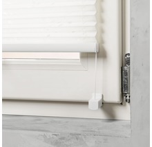 Detaljvy av en vit plisségardin i fönstret