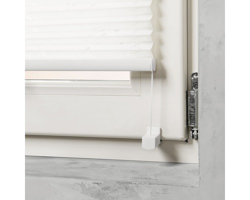 Detaljvy av en vit plisségardin i fönstret