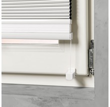 Detaljvy av en vit plisségardin på ett fönster